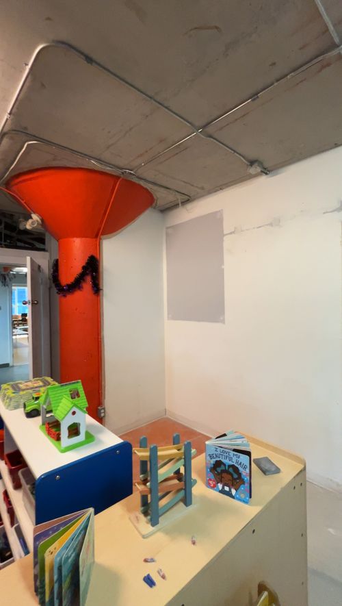 Daycare playroom before: orange column and patched walls
